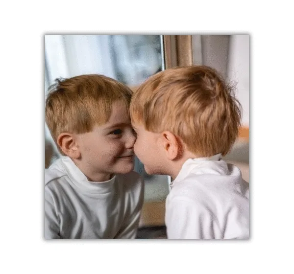 niño pequeño mirándose en el espejo y sonriendo